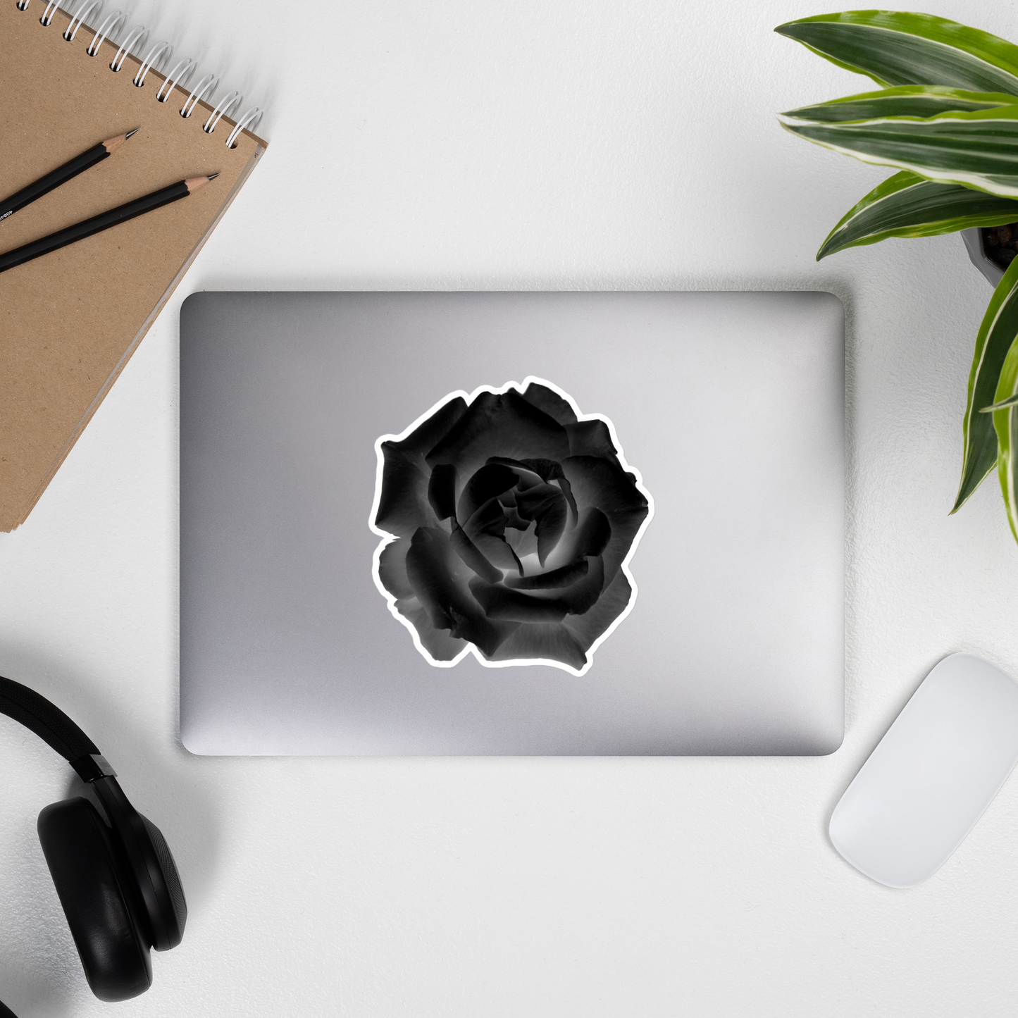 Lifestyle photo of a kiss-cut vinyl sticker with an image of a black x-ray rose design, placed on the outside of a laptop.