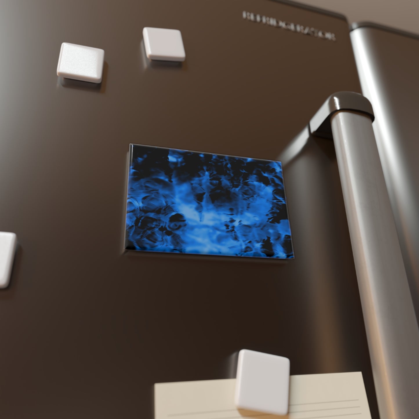 Lifestyle photo of a rectangular button magnet with an image of a vivid blue and black water reflection design, placed on a fridge.
