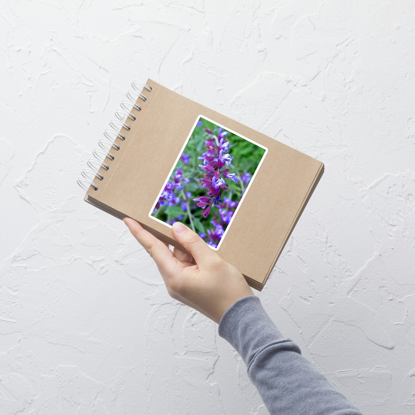 Lifestyle photo of a rectangular vinyl sticker with a close-up image of purple sage, placed on a small notepad.