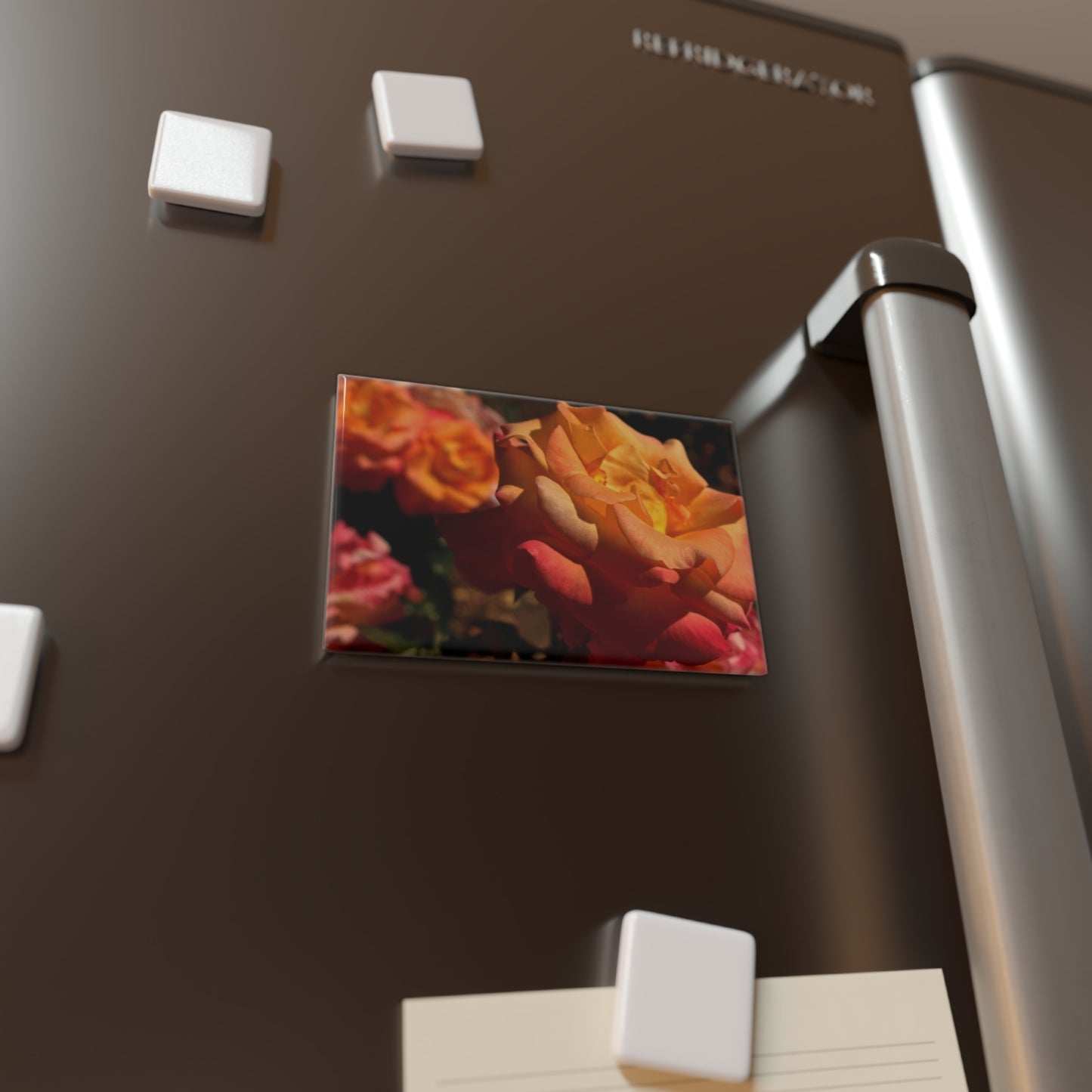 Lifestyle photo of a rectangular button magnet with an image of a cluster of sunset-toned blush roses, placed on a fridge.