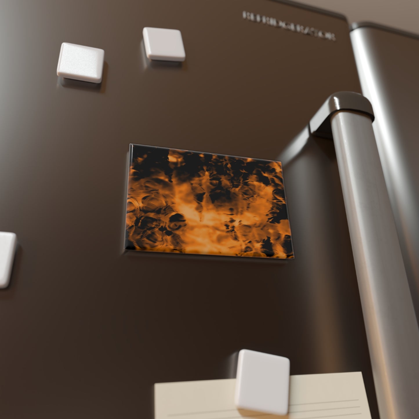 Lifestyle photo of a rectangular button magnet with an image of a vivid orange and black water reflection design, placed on a fridge.