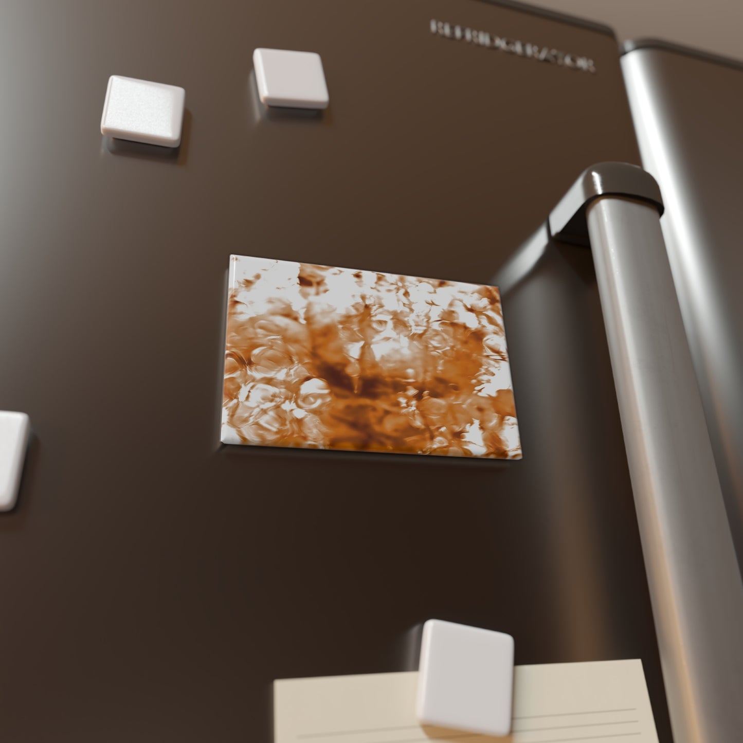 Lifestyle photo of a rectangular button magnet with an image of a vivid orange water reflection design, placed on a fridge.