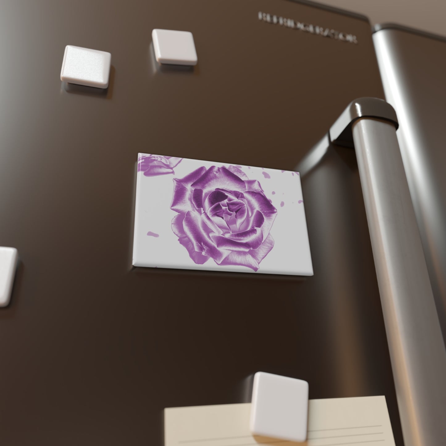 Lifestyle photo of a rectangular button magnet with an image of a pink reflective rose design, placed on a fridge.