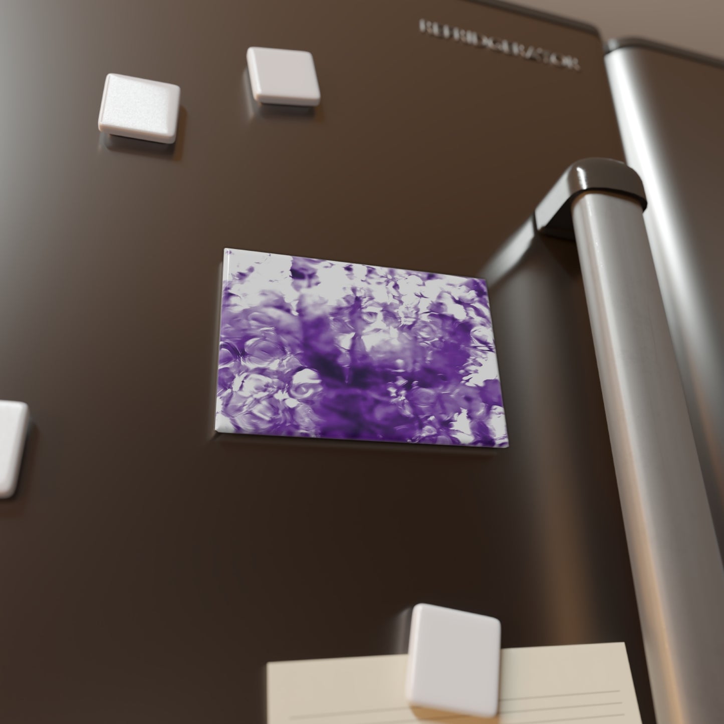 Lifestyle photo of a rectangular button magnet with an image of a vivid purple water reflection design, placed on a fridge.