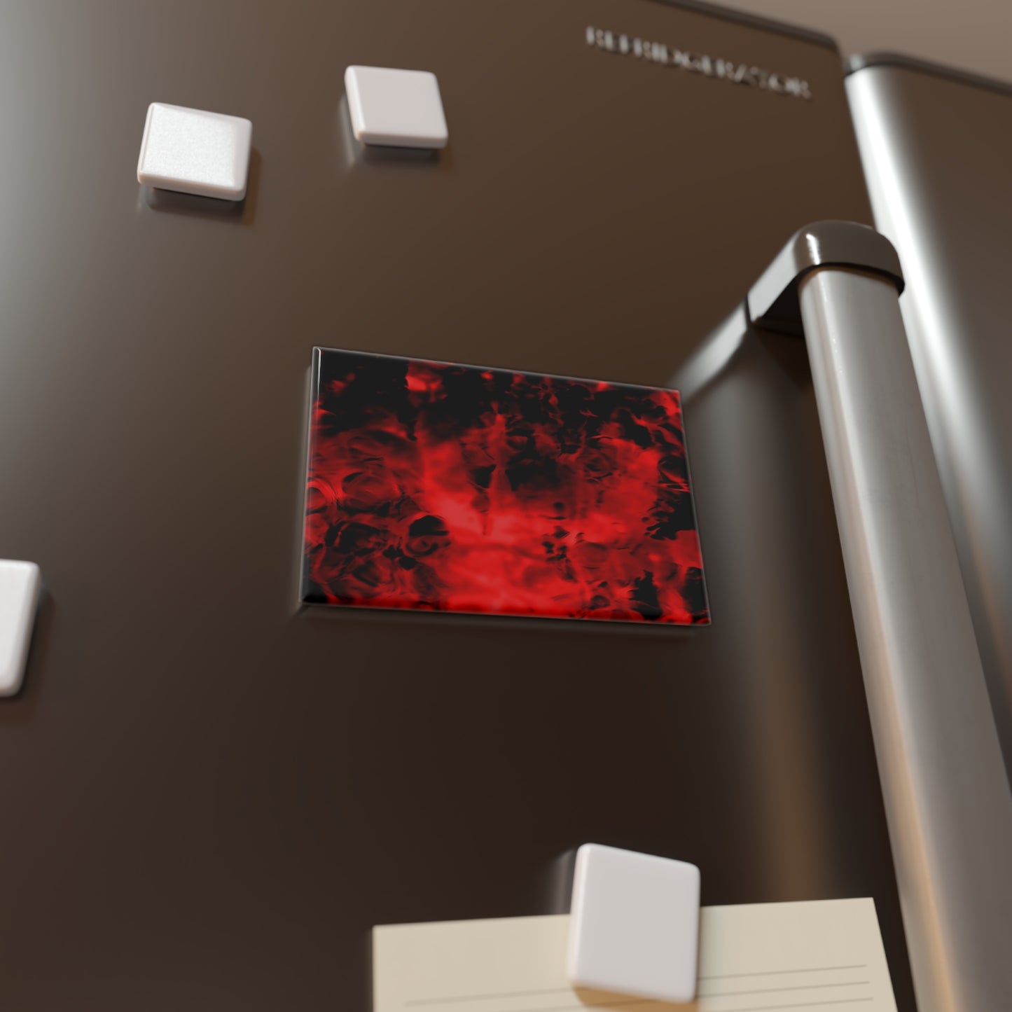Lifestyle photo of a rectangular button magnet with an image of a vivid red and black water reflection design, placed on a fridge.