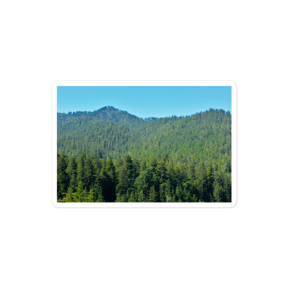 A medium rectangular vinyl sticker with an image of mountain landscape with redwood trees and blue sky.