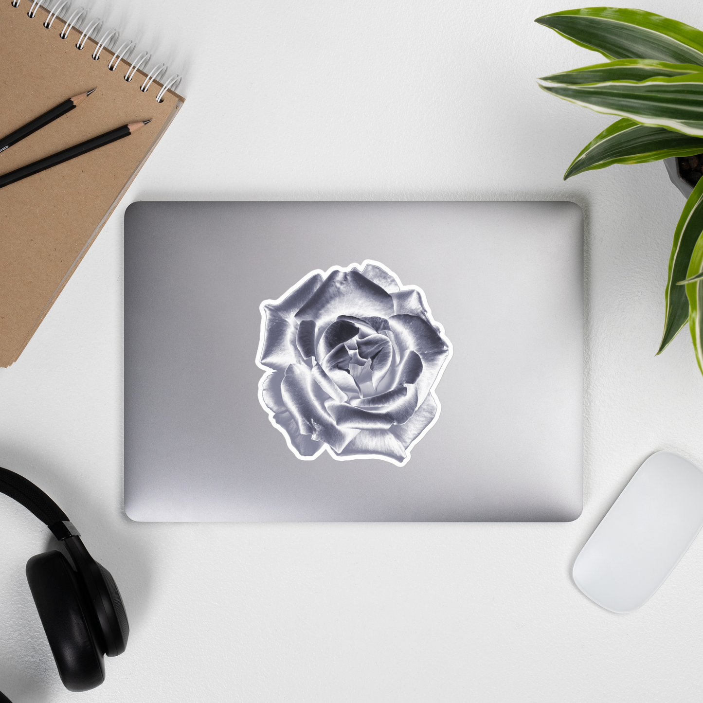 Lifestyle photo of a kiss-cut vinyl sticker with an image of a silver reflective rose, placed on the outside of a laptop.
