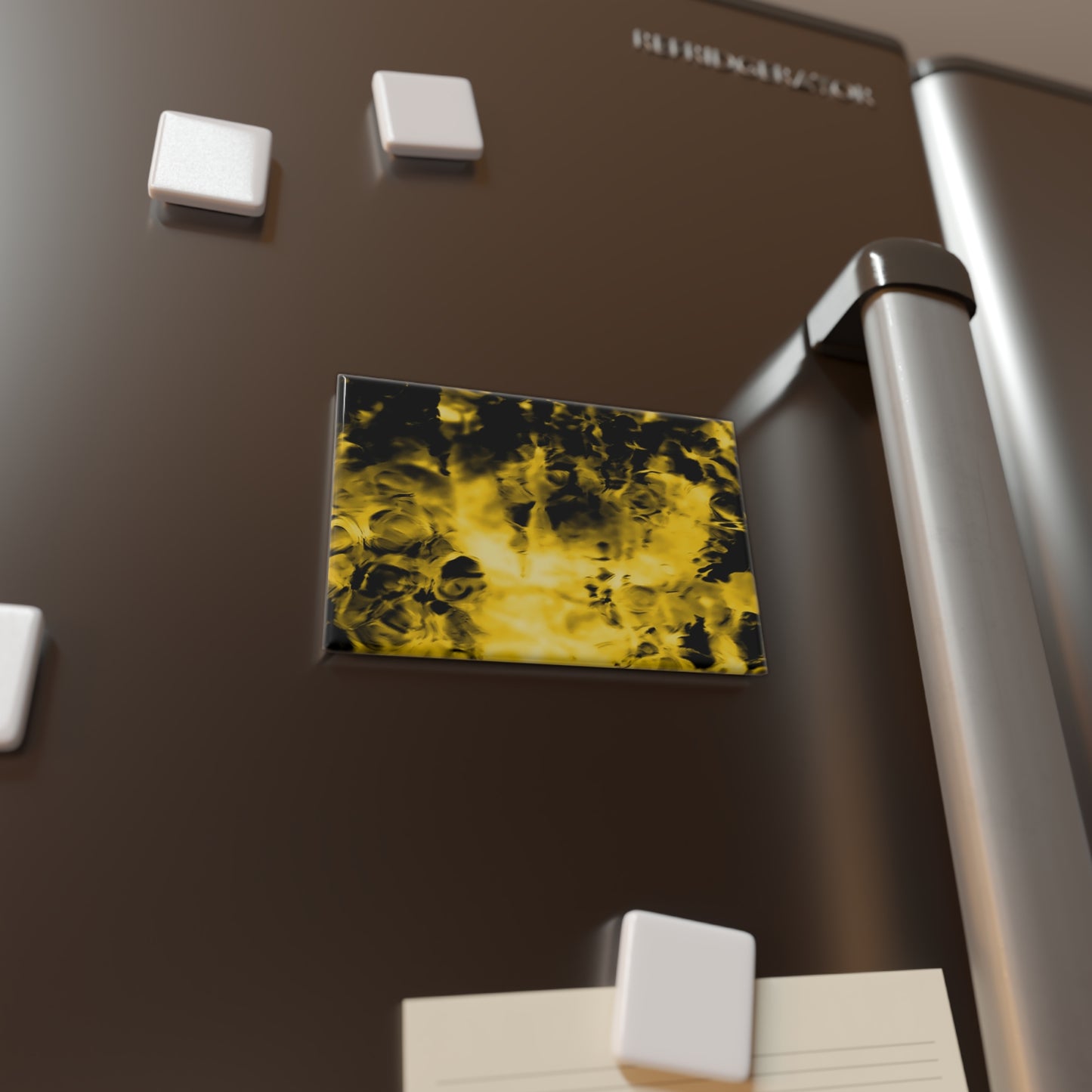 Lifestyle photo of a rectangular button magnet with an image of a vivid yellow and black water reflection design, placed on a fridge.