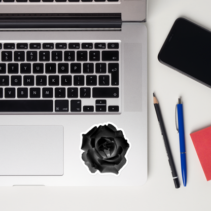 Lifestyle photo of a kiss-cut vinyl sticker with an image of a black x-ray rose design, placed on a laptop to the right of the mouse pad.