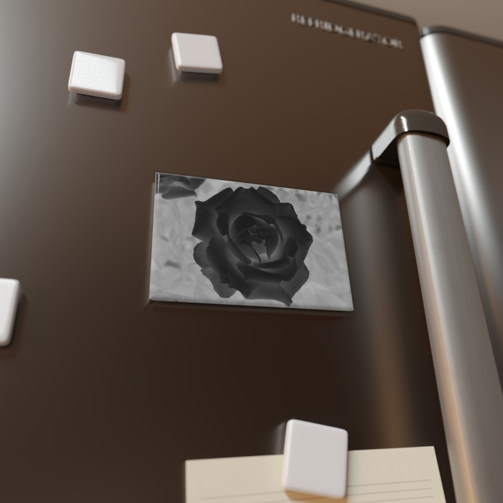Lifestyle photo of a rectangular button magnet with an image of a black x-ray rose design, placed on a fridge.