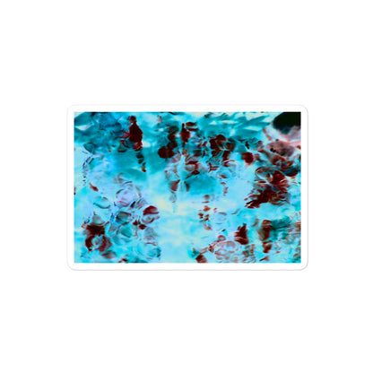 A medium rectangular vinyl sticker with an image of a vivid blue and red water reflection design.