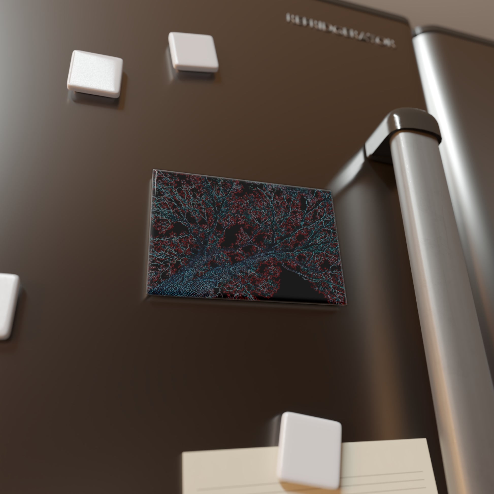 Lifestyle photo of a rectangular button magnet with an image of a neon blue and red tree design with lightning like features, placed on a fridge.