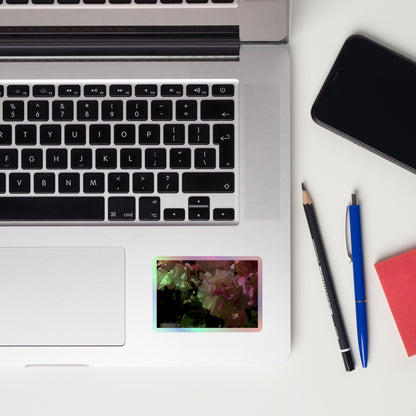 Lifestyle photo of a rectangular holographic sticker with an image of pink tipped white rose blooms, placed on a laptop to the right of the mouse pad.