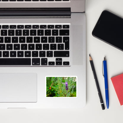 Lifestyle photo of a rectangular vinyl sticker with an image of a lavender bloom in an herb garden, placed on a laptop to the right of the mouse pad.