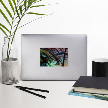 Lifestyle photo of a rectangular holographic sticker with an image ofgolden purple foxtails breeze, placed on a laptop with desk supplies nearby.