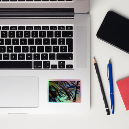 Lifestyle photo of a rectangular holographic sticker with an image ofgolden purple foxtails breeze, placed on a laptop to the right of the mouse pad.