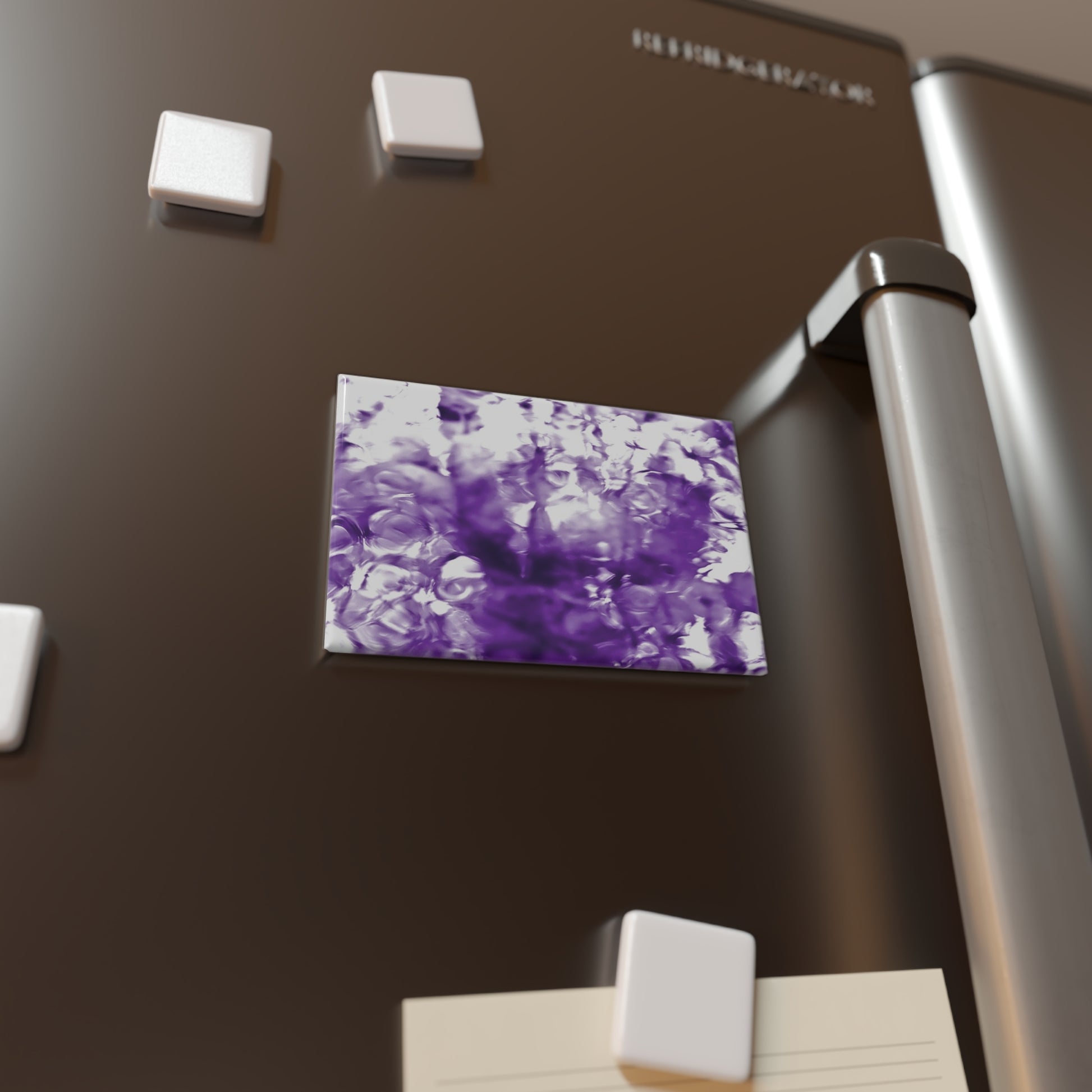 Lifestyle photo of a rectangular button magnet with an image of a vivid purple water reflection design, placed on a fridge.