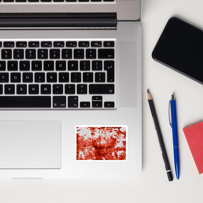 Lifestyle photo of a rectangular vinyl sticker with an image of a vivid red water reflection design, placed on a laptop to the right of the mouse pad.