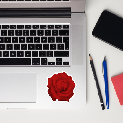 Lifestyle photo of a kiss-cut vinyl sticker with an image of a vivid red rose design, placed on a laptop to the right of the mouse pad.