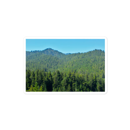 A medium rectangular vinyl sticker with an image of mountain landscape with redwood trees and blue sky.