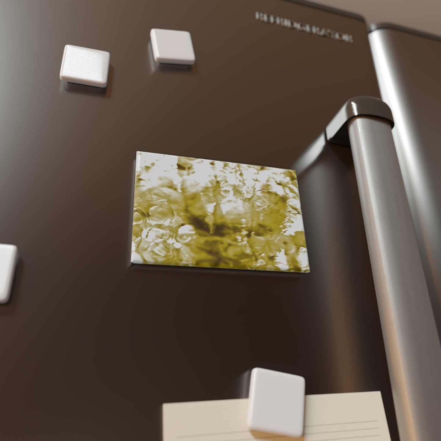 Lifestyle photo of a rectangular button magnet with an image of a vivid yellow water reflection design, placed on a fridge.